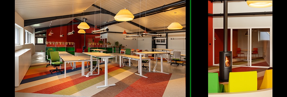 Rangée de bureaux à plateaux réglables sur sol à bandes colorées, et coin détente au poêle à bois derrière un vitrage