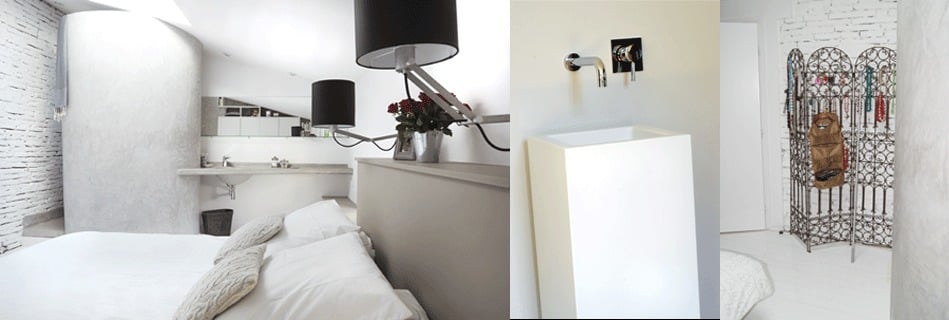 Chambre des parents en boîte suspendue dans le volume du chai : douche en escargot et vasque en tadelakt gris intégrées, lit blanc et suspensions à abat-jour noir