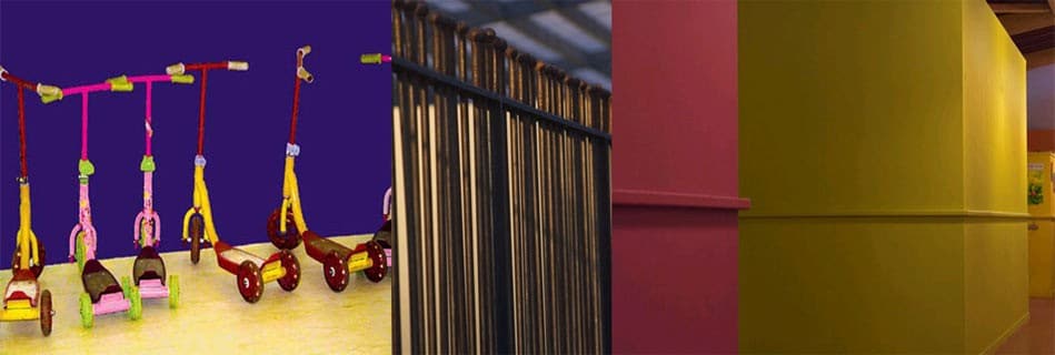 Trottinettes colorées des enfants sur fond violet, clôture métallique et jeu de murs framboise et jaune