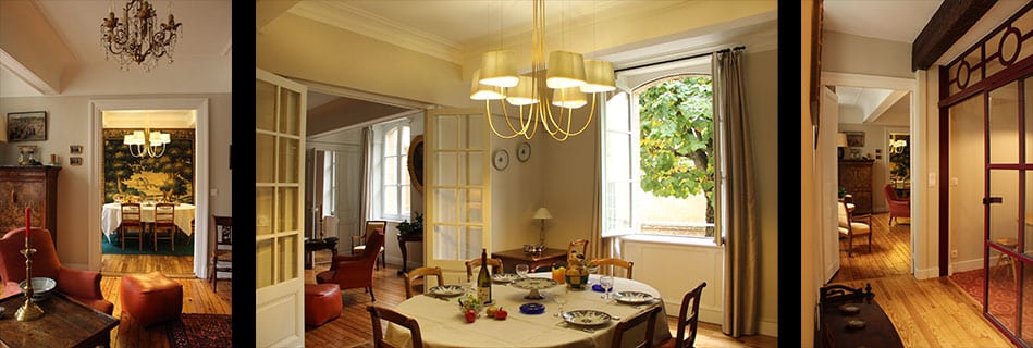 Salle à manger sous un lustre en laiton, table dressée devant la fenêtre ouverte sur le tilleul de la cour, enfilade de pièces en parquet et verrière