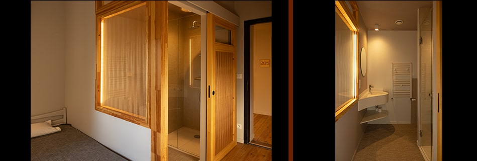 Chambre avec salle d'eau vitrée à cloison bois et cabine de douche, porte de chambre numérotée 205