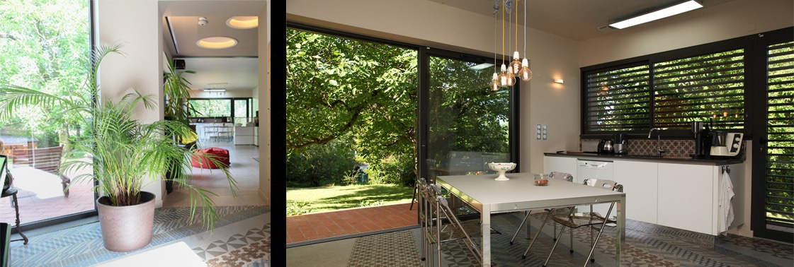 La cuisine-repas ouverte sur le jardin par de grandes baies vitrées, table sur sol en carreaux de ciment et brise-soleil filtrant la lumière