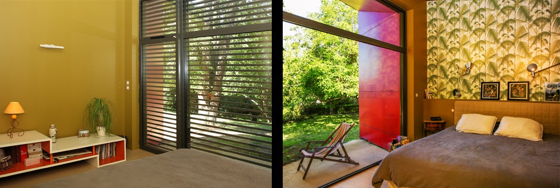 Chambre parentale aux murs ocre, baie vitrée à brise-soleil et grande verrière colorée rouge ouvrant sur le jardin depuis la tête de lit papier peint tropical