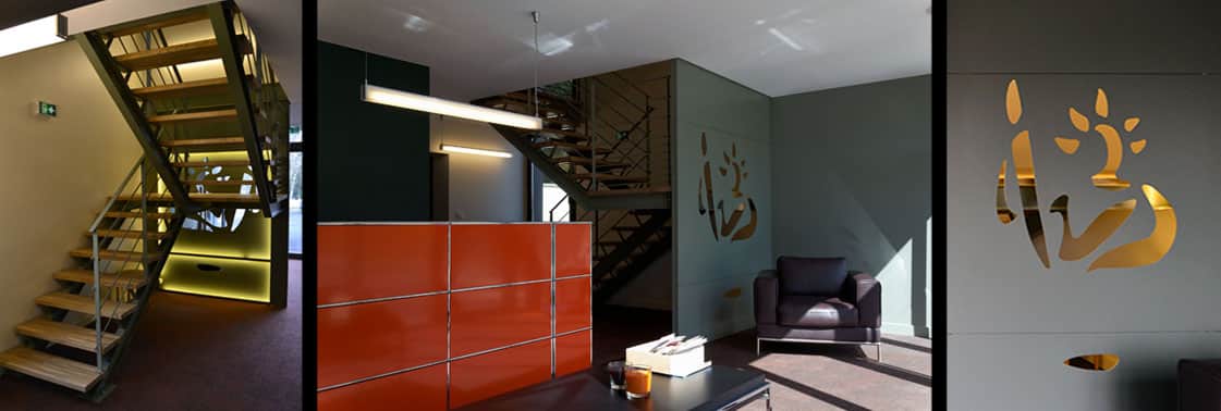Escalier bois et acier rétroéclairé de vert, accueil au meuble orange et fauteuil cuir sous l'emblème notarial doré découpé sur un mur gris