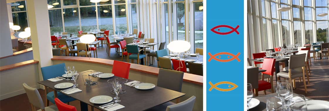Salle à manger aux chaises colorées ouverte sur la rivière par de hautes baies courbes, et logo des trois poissons rouge, orange et jaune